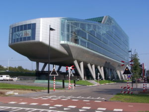 Picture of a beautiful glass ING Bank in Amsterdam on stilts, by a railroad track.