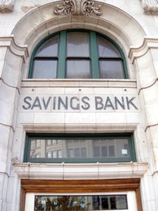 Picture of the phrase "Savings Bank" placed high on a stone bank facade.